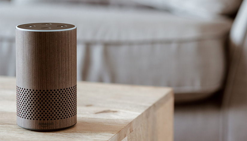 Smarter Lautsprecher steht auf einem Holztisch in einem Wohnzimmer